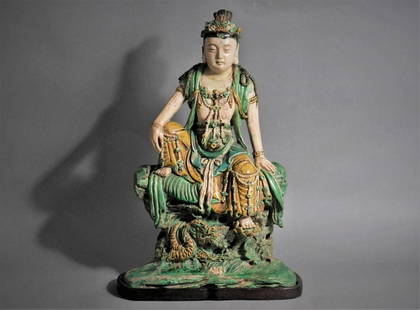 LARGE CHINESE GLAZED TILEWORKS FIGURE OF GUANYIN: Ming-early Qing Dynasty, 16th-17th century Seated in rajlilasana with right arm resting on right knee, the left foot supported by a lotus blossom, the dragon below emerging from rock-work. Height