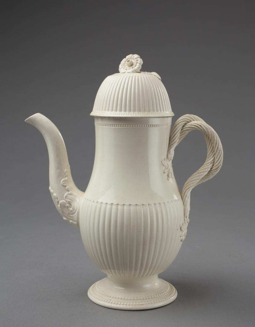 CREAMWARE COFFEE POT WITH RIBBED LOWER HALF OF BODY: Leeds, circa 1770. The vertical reeding on lower body and on domed lid; flower finial; twisted and entwined rope handles. Author John D. Griffin (Leeds Pottery Volume I page 207 Figure 25`) believes t