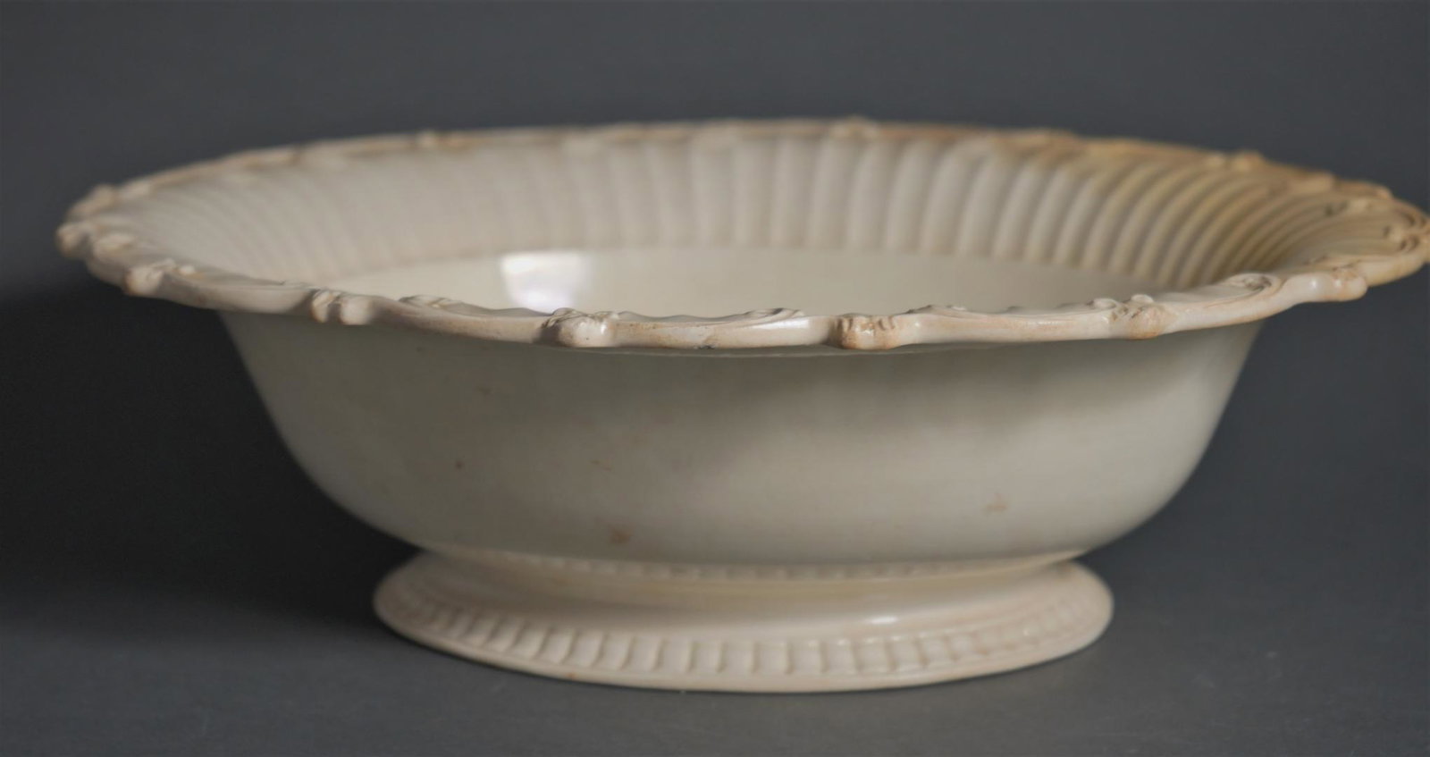 SCALLOPED, FLUTED, FOOTED CREAMWARE PUNCH BOWL: English, circa. 1780. Creamware Scalloped, Fluted, Footed Creamware Punch Bowl. Provenance: Wynn A Sayman; A Distinguished New York Collection of Creamware Dimensions: Length : 13 3/8 inches Width : 1