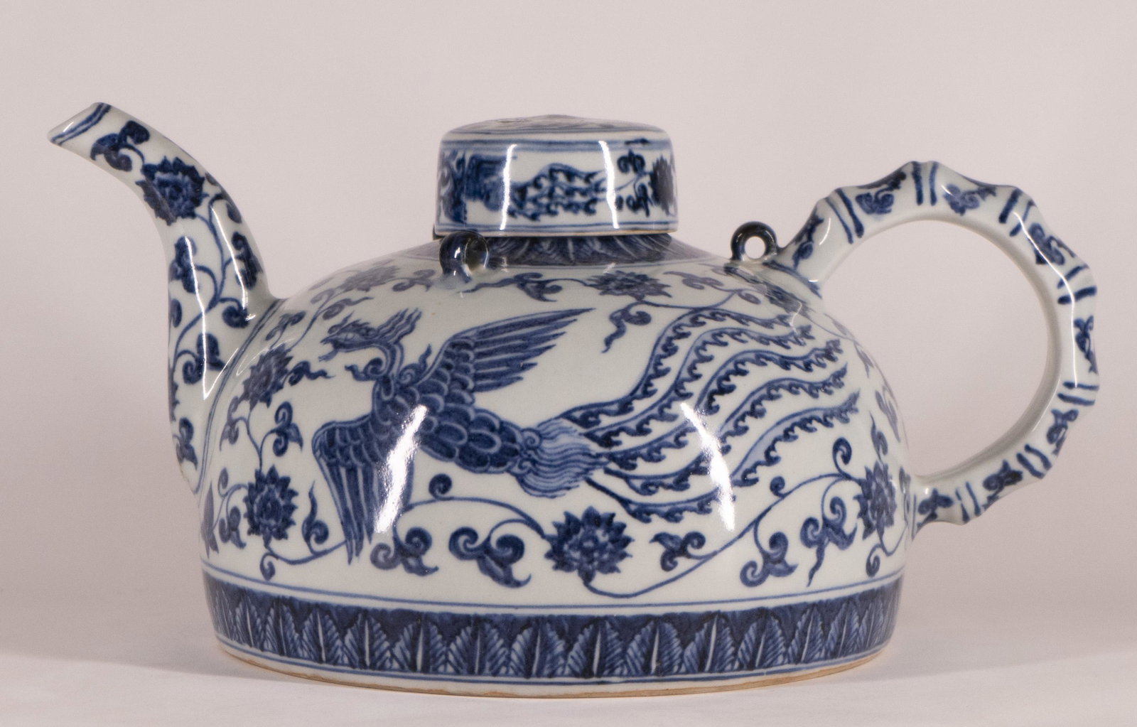 Chinese Blue and White Porcelain Covered Teapot: In Ming Dynasty (15th Century) Taste Domed body with phoenixes and floral vines, lotus leaf lappet border at the bottom. H. 6 1/4 in., D. 7 3/4 in. Condition: Hairline crack just above the pouring spo