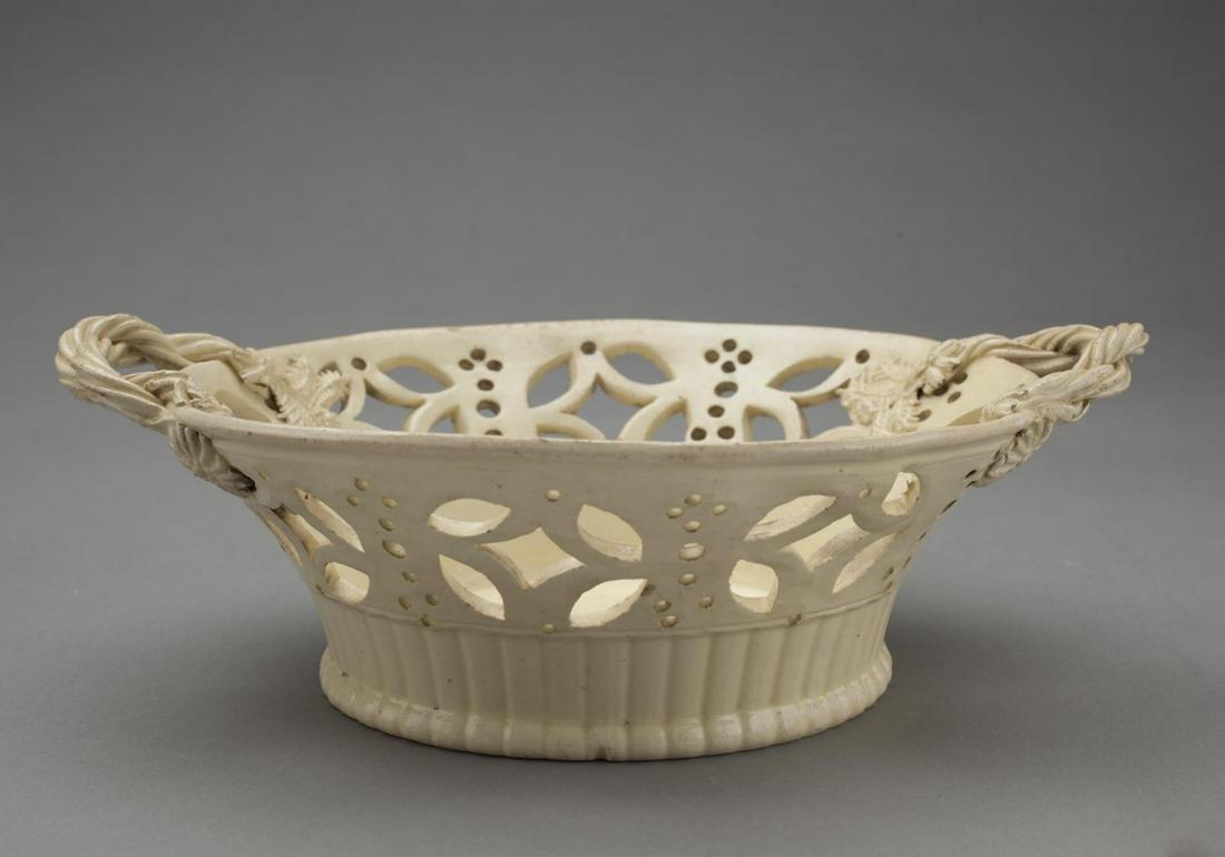 Creamware Fruit Bowl with Rope Twist Handles: English, circa 1770. With boldly twisted rope handles; a wide band of piercing beneath rim. H. 3 1/8 in., L. 9 1/4 in. Provenance: A Distinguished Orange County, New York Collection of Creamware Condi