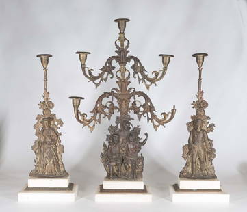 Victorian Gilt Metal and Marble Figural Garniture: American 19th century Comprising a candelabra centerpiece and two figural candlesticks, white marble bases. Centerpiece, H. 23 in. Condition: centerpiece is missing one bobeche and missing all