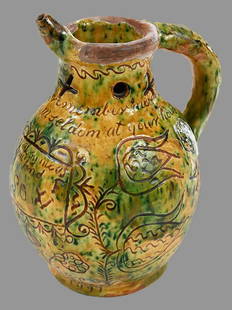 Rare Donyatt Incised Slipware Puzzle Jug: British, Donyatt, Somerset, circa 1790 Oviform with yellow and mottled green glaze, sgraffito and pierced neck, tubular rim with a single spout, shoulder incised with the drinking verse, "When