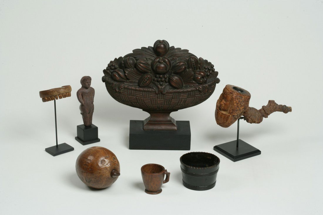 A Group of Seven Assorted Decorative Objects (7): A Group of Seven Assorted Decorative Objects 19th/early 20th century Comprising of a burl wood cup, a set of carved wooden teeth, terracotta fig of a man, burl pipe in form of wigged man (possibly Geo