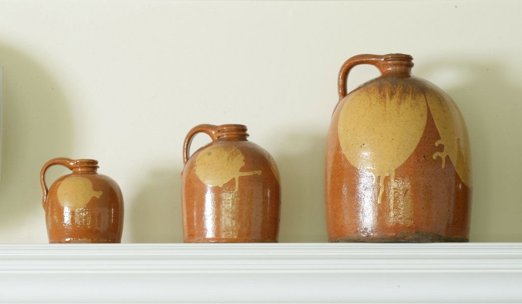 Set Of Three Slip-Decorated Redware "Moon" Jugs: Galena, Illinois, mid-19th century The largest jug inscribed on handle: "2" (gallons) (3) Provenance: Walters Benisek Art and Antiques, Northampton, Massachusetts, March 9, 1996 Estimate: $2,000 - $4,