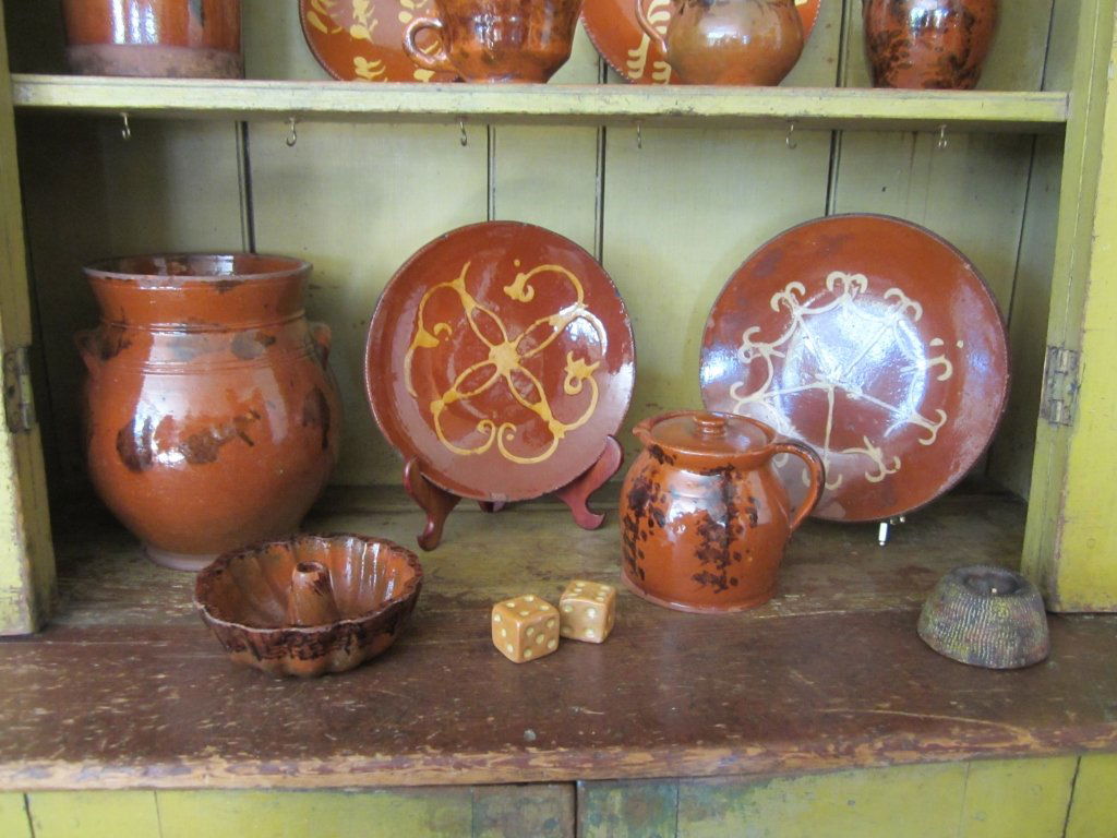 Three Redware Vessels and Two Slipware Plates: Together with a Pair of Yellow Ware Dice and Earthenware Match Strike American, 19th century The manganese decorated jar with applied handles, the cake mold with manganese and copper oxide decoration,