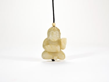 A Chinese Yellowish-Celadon Jade Figure of a Seated Boy Pendant. Qing Dynasty