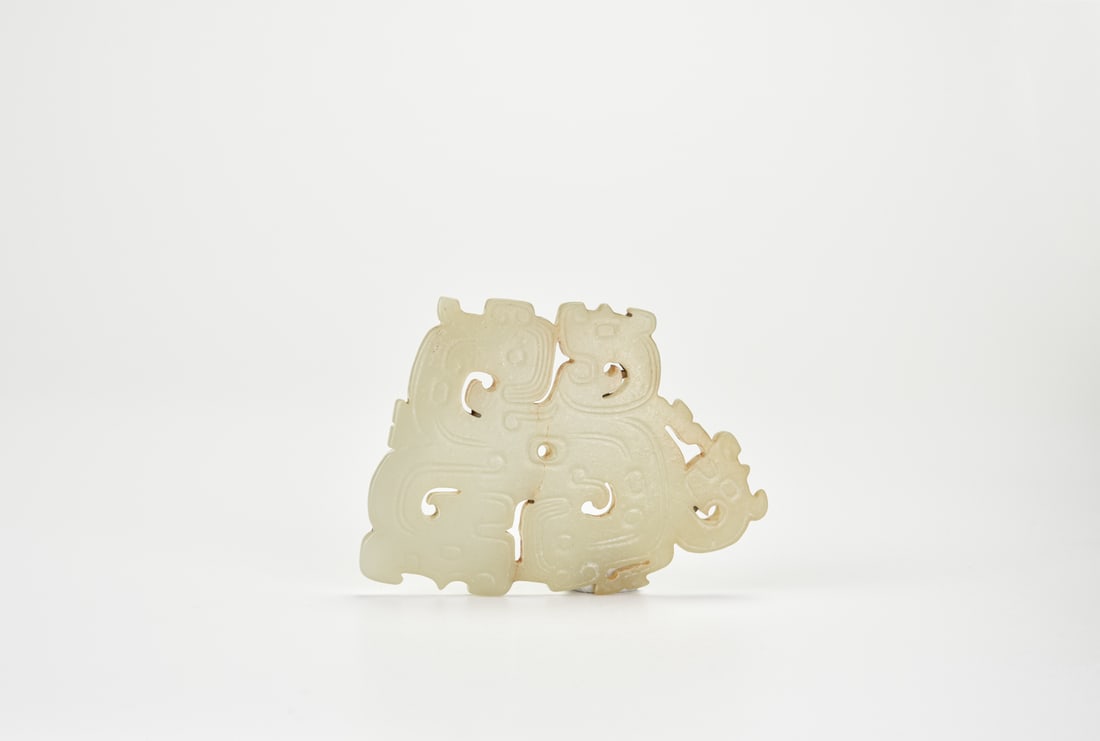 A Celadon Jade Openwork Plaque Carved with Taotie Mask, Shang to Western Zhou Dynasty (circa: A Celadon Jade Openwork Plaque Carved with Taotie Mask, Shang to Western Zhou Dynasty (circa 13th–9th Century BC)This jade plaque is finely carved in openwork with a stylized taotie mask design.