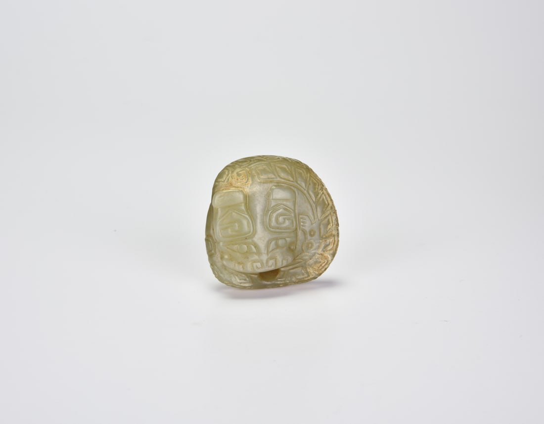 A Rare Archaic Jade Coiled Dragon (“Juanwei Long??)Shang Dynasty (c. 13th–11th century BCE): A Rare Archaic Jade Coiled Dragon (“Juanwei Long”)Shang Dynasty (c. 13th–11th century BCE)Carved from translucent celadon jade with areas of calcification and russet inclusions, the