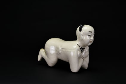 A Chinese Cream-Glazed Porcelain Pillow in the Form of a Reclining Boy, Qing Dynasty