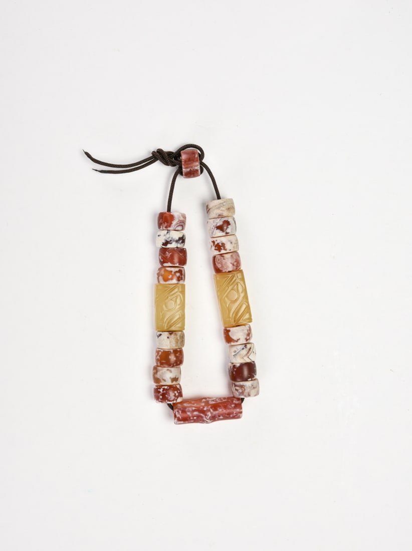 Western Zhou Dynasty, A Bead Bracelet: Composed of cylindrical agate beads in variegated red and white tones, showing natural marbling and pale inclusions. Interspersed with tubular jade elements of pale yellow tone, each carved with simpl