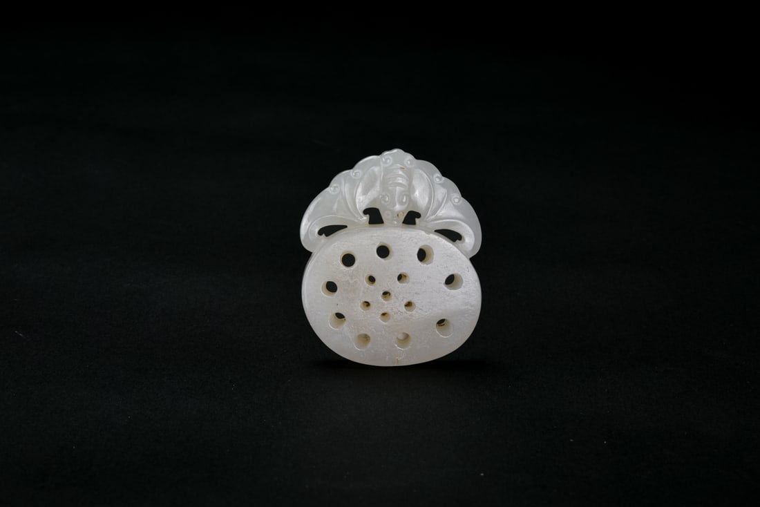 A Chinese Jade ‘Bat and Fruit’ Pendant China, Qing Dynasty (18th–19th century).: Carved from pale jade with natural inclusions. The pendant is worked in openwork relief depicting bats in flight amidst fruiting forms, the composition balanced and well spaced. The carving is smoothl