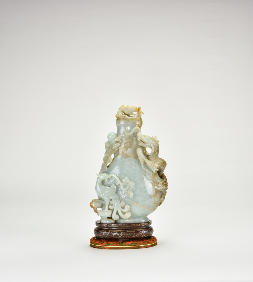 A Fine Jadeite ‘Dragon and Phoenix’ Covered Vase (wood stand/box), Republic.: Carved from a single block of natural jadeite of fine texture and good translucencyJadeite Vase Only H: 8 3/4 In (19.5 cm) W: 4 1/2 In (11.5 cm)民國-翡翠巧色雕