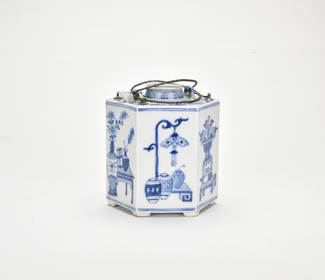 Late Qing To Republic Period. A Blue-And-White Porcelain Hexagonal Warming Wine Vessel,: decorated with bogu motifs, comprising an outer container and a removable inner pot with metal handle.H: 5 1/8 In (13 cm) W: 4 3/4 In (11.7 cm)清末至民國 青花