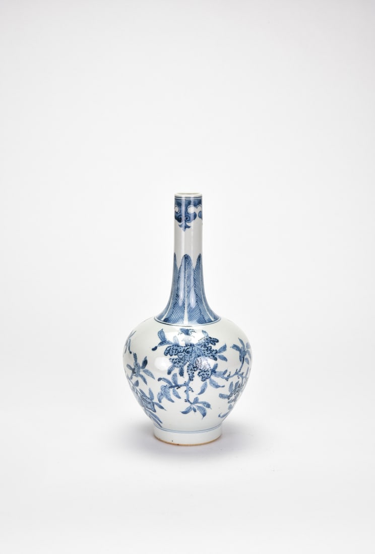 Late Qing. A Chinese Blue and White Long-Neck Vase, Qianlong Mark: Of pear-shaped form rising to a tall cylindrical neck, painted in underglaze blue with stylized floral scrolls borne on leafy tendrils, the neck decorated with upright lappets and ruyi-cloud bands. Th
