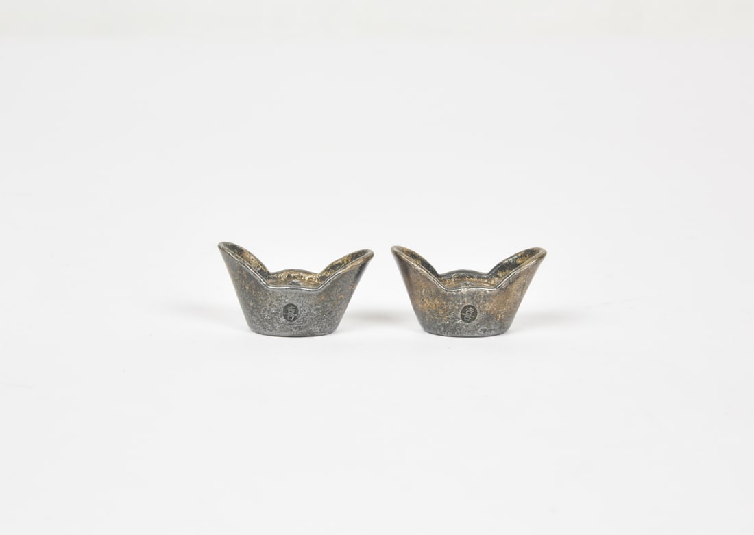 Two Chinese Silver Sycee (Yuanbao) Ingots, Qing Dynasty: Each cast in compressed oval form with upturned ends and a central interior knop. The bases are stamped “Dongchang,” “Pure Silver,” “One Tael,” and serial number &#