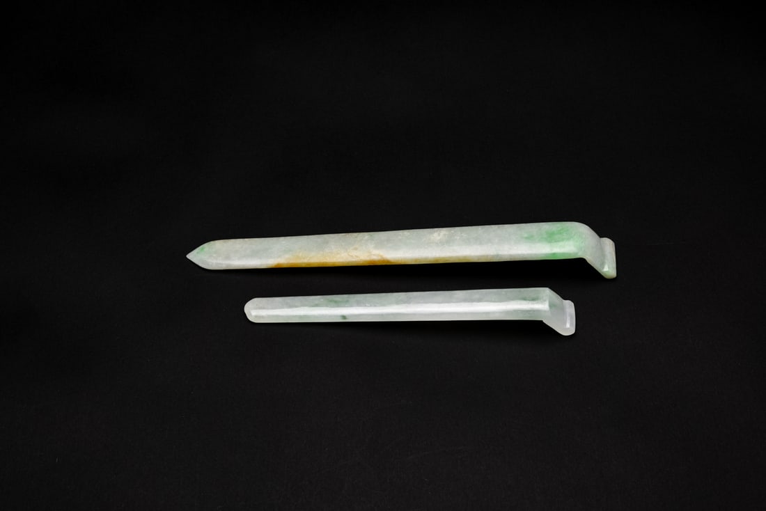 Two Jadeite Hairpins Qing Dynasty/Republic: Carved from jadeite with smoothly polished surfaces. One example displays vivid green and yellow inclusions, while the other is of semi-translucent quality with an even lustrous finish, emphasizing th