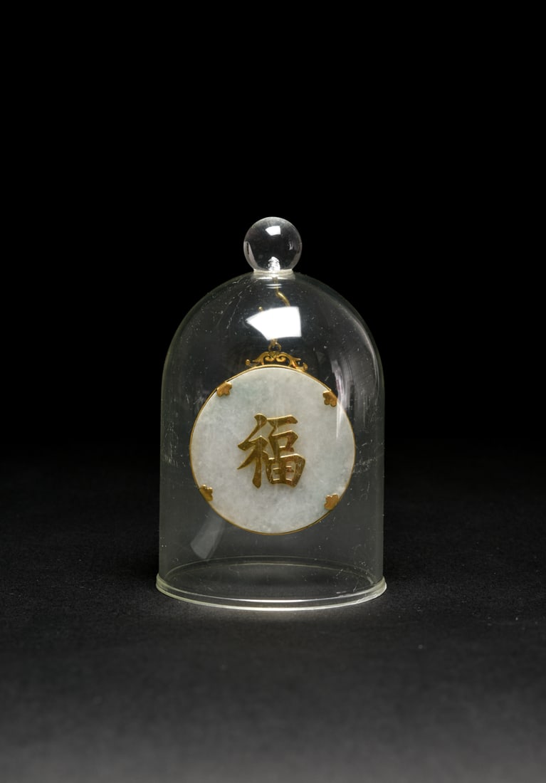 A Jadeite Jade, Gold and Multi-Colored Gem-Set ?Crane? Pendant with Dome Display: The circular semi-translucent jadeite plaque, mounted to the front with two cranes amidst flowering branches and grasses, rendered in finely worked and applied gold. The composition highlighted with c