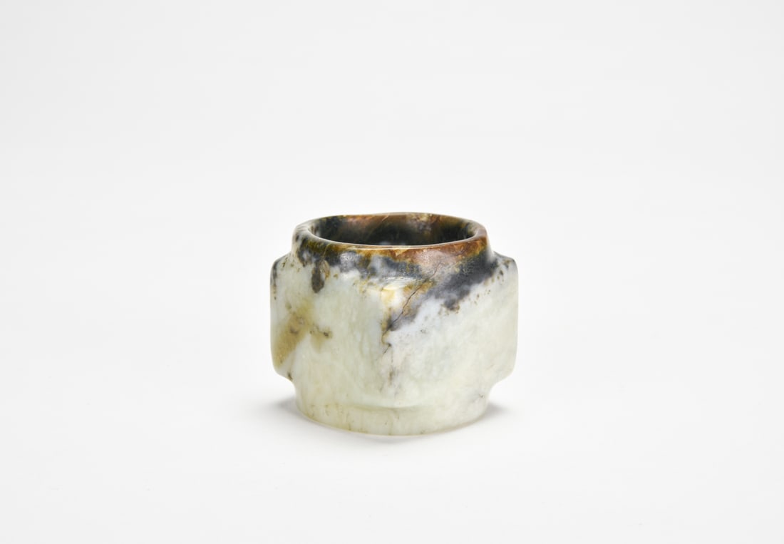 A Jade Cong, Qijia Culture: The cong of slightly tapering square section carved from a pale celadon jade with extensive black, russet, and cream inclusions. The exterior corners subtly rounded, with shallow medial ridges definin