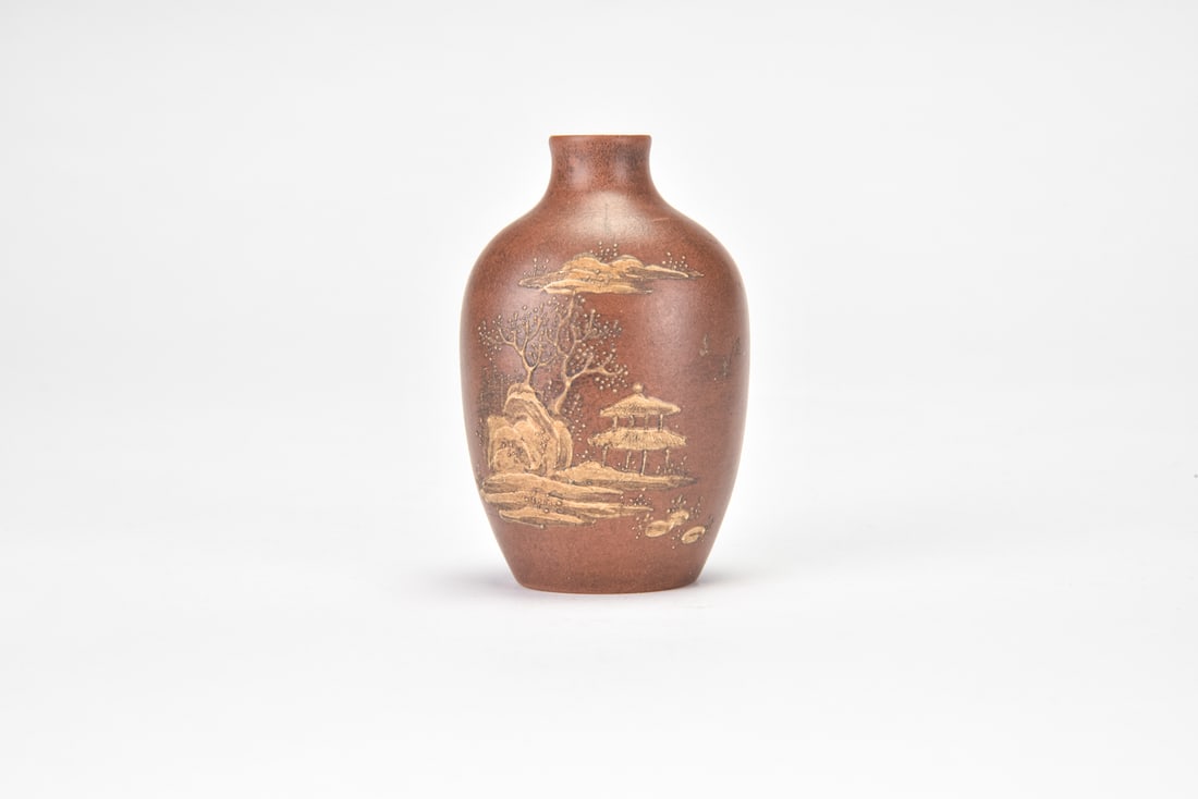 A Yixing Zisha Slip-Decorated Landscape Snuff Bottle: The snuff bottle is finely potted of reddish-brown Yixing stoneware, with a rounded ovoid body rising to a short cylindrical neck and small mouth. The exterior is decorated in contrasting pale slip