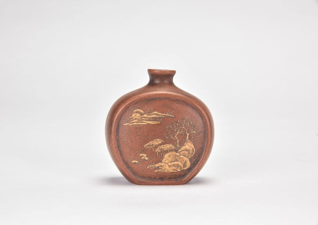 A Yixing Zisha Slip-Decorated Landscape And Prunus Snuff Bottle: The flattened circular snuff bottle is finely potted of reddish-brown Yixing stoneware, with a short waisted neck and gently flared mouth. One side is decorated in contrasting pale slip with a