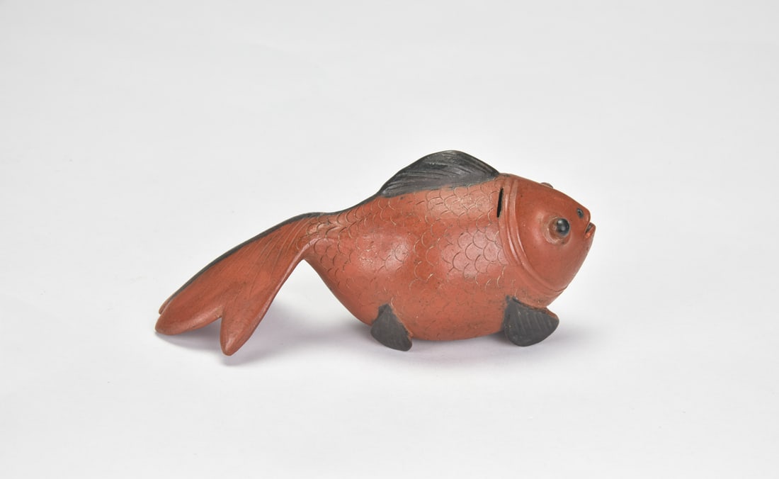 A Yixing Zisha Fish-Form Water Dropper. Jian Ji Mark: Naturalistically modeled in the form of a plump fish, the water dropper is fashioned from reddish-brown Yixing stoneware, its body finely incised with overlapping scales and applied with contrasting