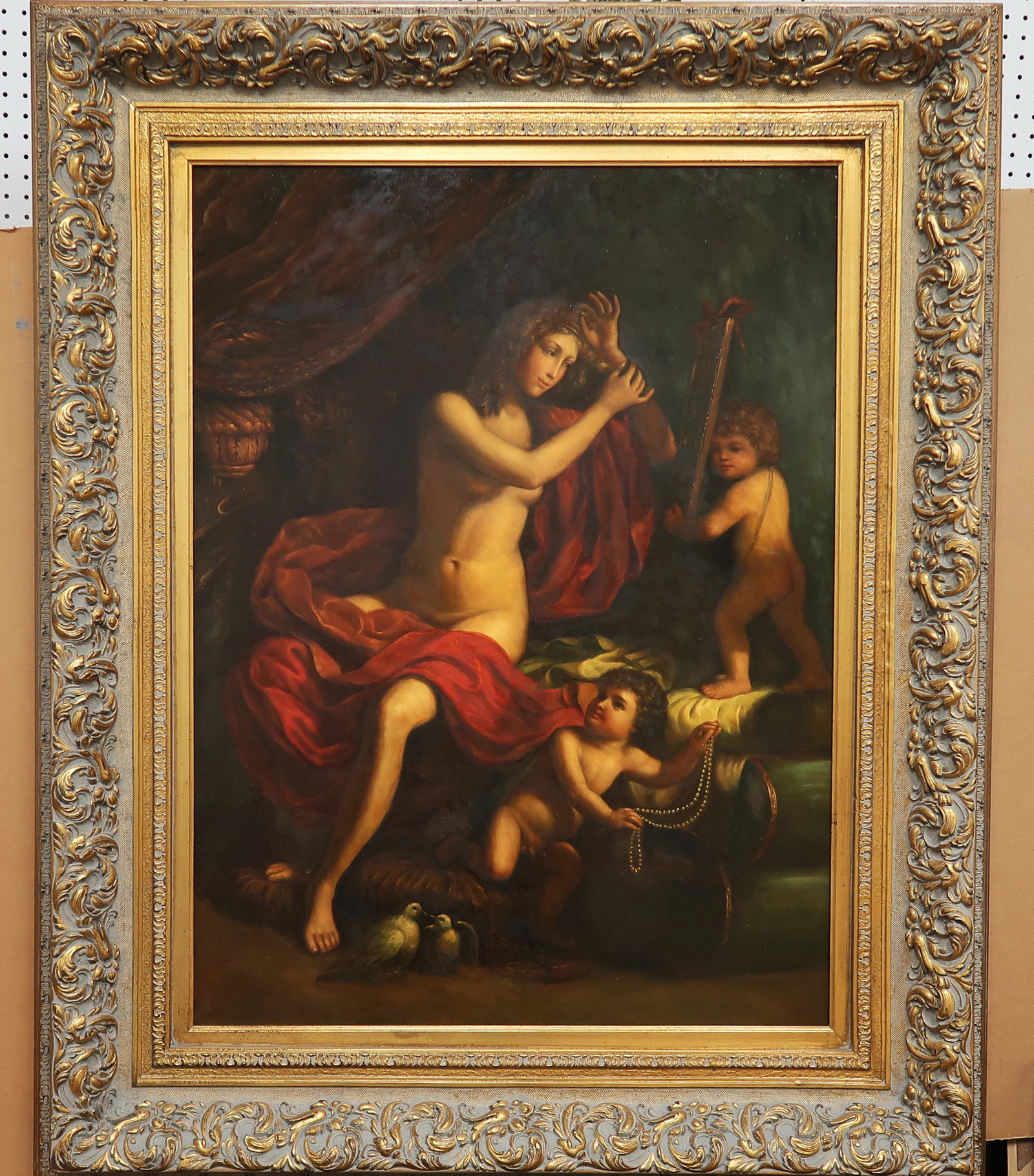 Oil on Canvas "LOVE": This antique oil painting features a nude woman half-draped in a red with two cherubs, one playing a harp, the other with a strand of pearls. Two doves at her feet invoke peace and perhaps a wedding n