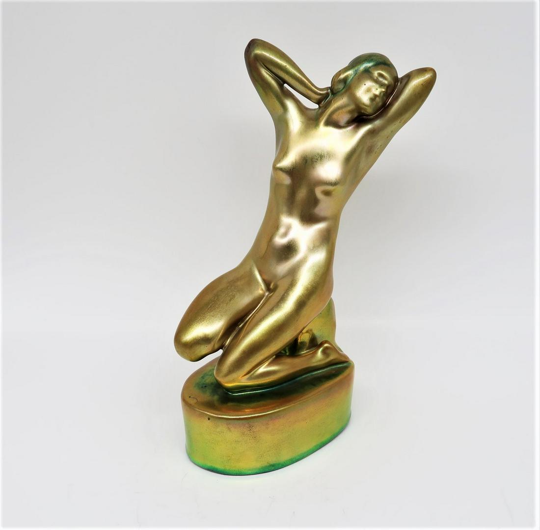 Zsolnay Nude Female Figure seated w/stamped: ZSOLNAY ART POTTERY FIGURE, a nude female figure seated, arms bent, hands behind her head. The iridescent green with blue highlights raised on attached ovoid plinth. Stamped Zsolnay Hungary underfoot.