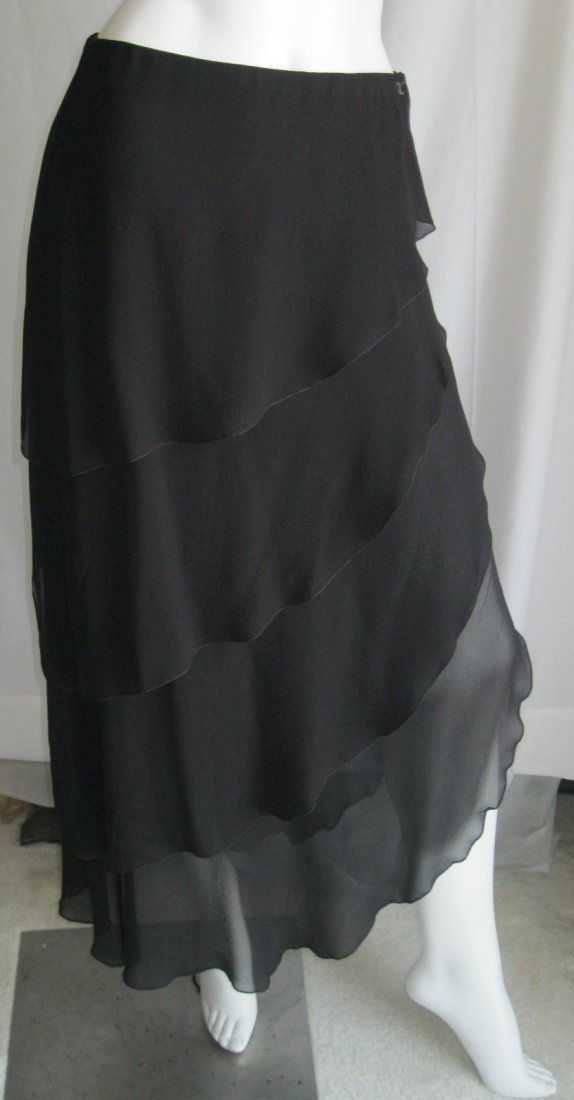 Chanel Black Layered Tiered Skirt: Beautiful Black Chanel Skirt with Tiered Layers, Side Slit and Side Zipper. Has a Small Chanel Logo Emblem sewn near the waist. Approximate Measurements-Waist 27", Length 37", Slit 15". Considered a S