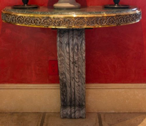 A pair of ormolu steel and grey variegated marble demi : A pair of ormolu steel and grey variegated marble demi lune console tables Each with steel top above a paneled frieze with foliate arabesques supported on scrolled fluted brackets, 19th century 39.25