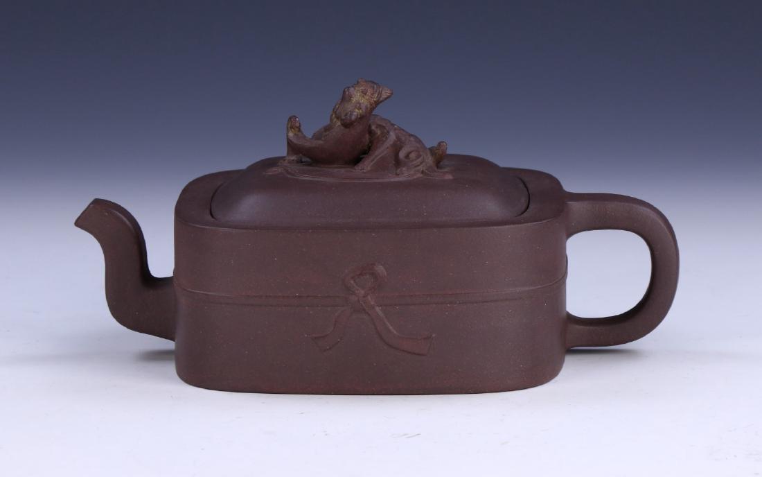A CHINESE YIXING ZISHA TEAPOT: A Chinese Yixing Zisha Teapot: Of Squared Form, Rising To A Domed Lid Topped With A Swirling Chi Dragon, Body Well Potted With A Curved Spout And C-Shaped Handle, Four Character Mark On The Base Withi