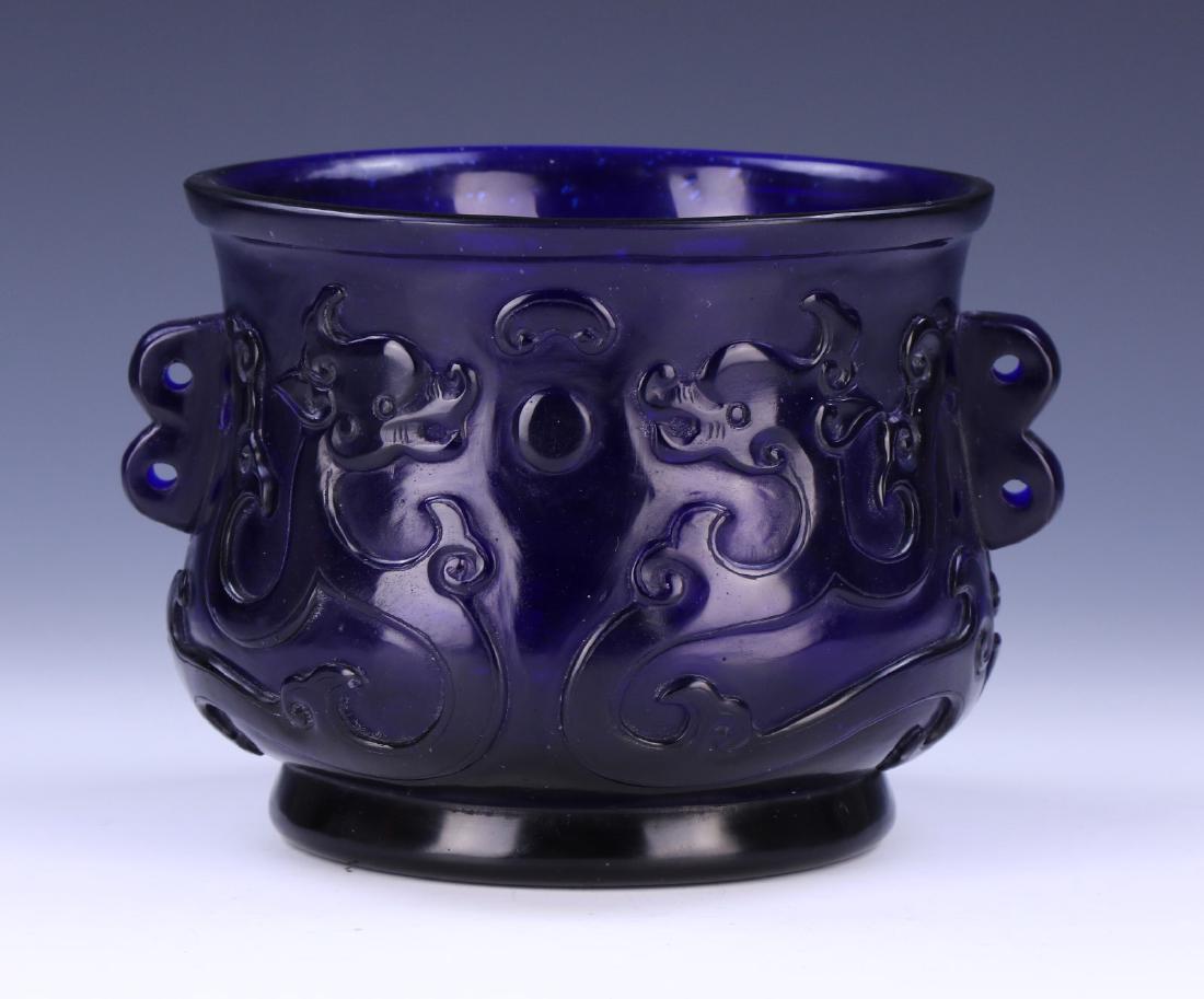 A CHINESE ANTIQUE BLUE PEKING GLASS JAR: A Chinese Antique Blue Peking Glass Jar: Of Pear Shape, Wide Neck Flanked One Each Side By Curling Handles, Body Finely Carved With Four Swirling Dragons Chasing Flaming Pearls, Four Character Qianlon