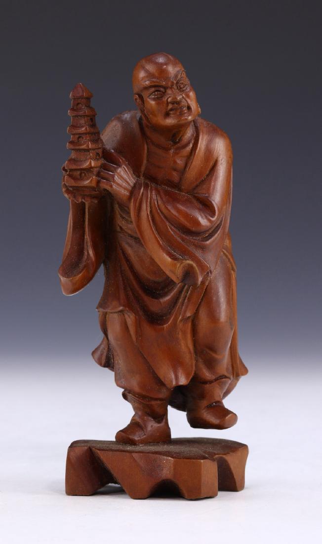 A CHINESE ANTIQUE WOOD CARVED FIGURE: A Chinese Antique Wood Carved Figure: Finely Carved, Rising From A Domed Openwork Plinth, Figure Shown in A Standing Position Draped in Loose Traditional Robes And Holding A Five Tiered Vessel, The Wo