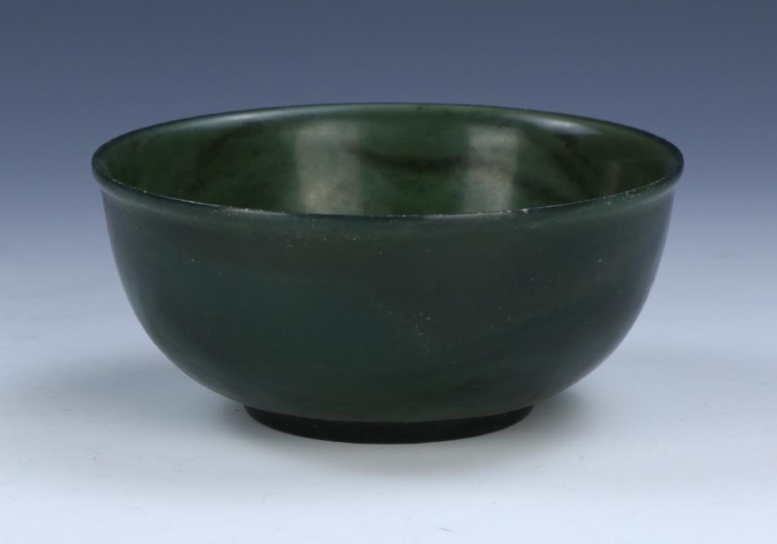 A CHINESE ANTIQUE SPINACH JADE BOWL: A Chinese Antique Spinach Jade Bowl: Skillfully Carved And Of Rounded Sides, Rising From A Base Rested On Low Feet To A Lipped Rim, The Semi Translucent Body Sculpted From Jade Of Mixed Medium To Dark