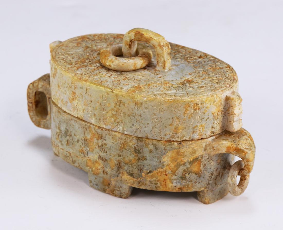 A Chinese Antique Archaic Jade Lidded Case: A Chinese Antique Archaic Jade Lidded Case: Of Oval Form, Lid With A Ring Handle Attached in The Center, Body With A Flared And Curling Handle; Size: L: 5-1/2" (13.97cm)