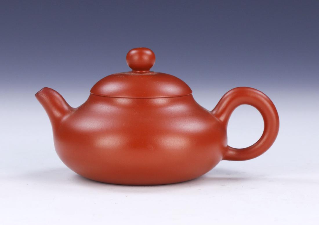 A CHINESE YIXING ZISHA TEAPOT: A Chinese Yixing Zisha Teapot: Of Compressed Globular Form, Four Character Mark On The Base Within A Square; Size: L: 5" (12.7cm)