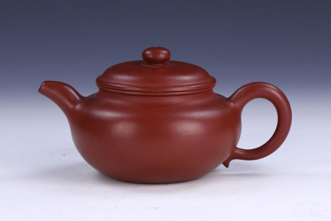A CHINESE YIXING ZISHA TEAPOT: A Chinese Yixing Zisha Teapot: Of Compressed Globular Form, Rising To A Domed Lid Topped With A Rounded Finial, Well Potted With A Curved Spout And C-Shaped Handle, Base incised With An inscription; S