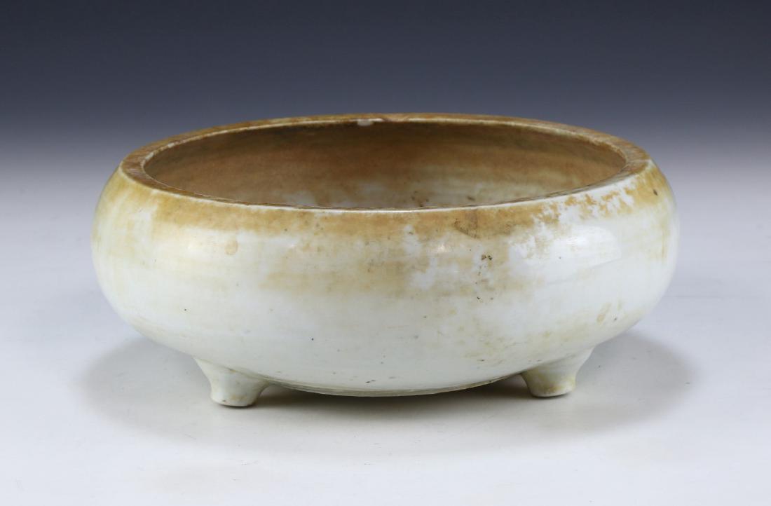 A CHINESE ANTIQUE WHITE GLAZED TRIPOD PORCELAIN WASHER: A Chinese Antique White Glazed Tripod Porcelain Washer: Well Potted With Rounded Sides, Rising From A Base Rested On Three Pegged Feet, Exterior Evenly Glazed in A Dulled White Tone; Size: D: 9" (22.8