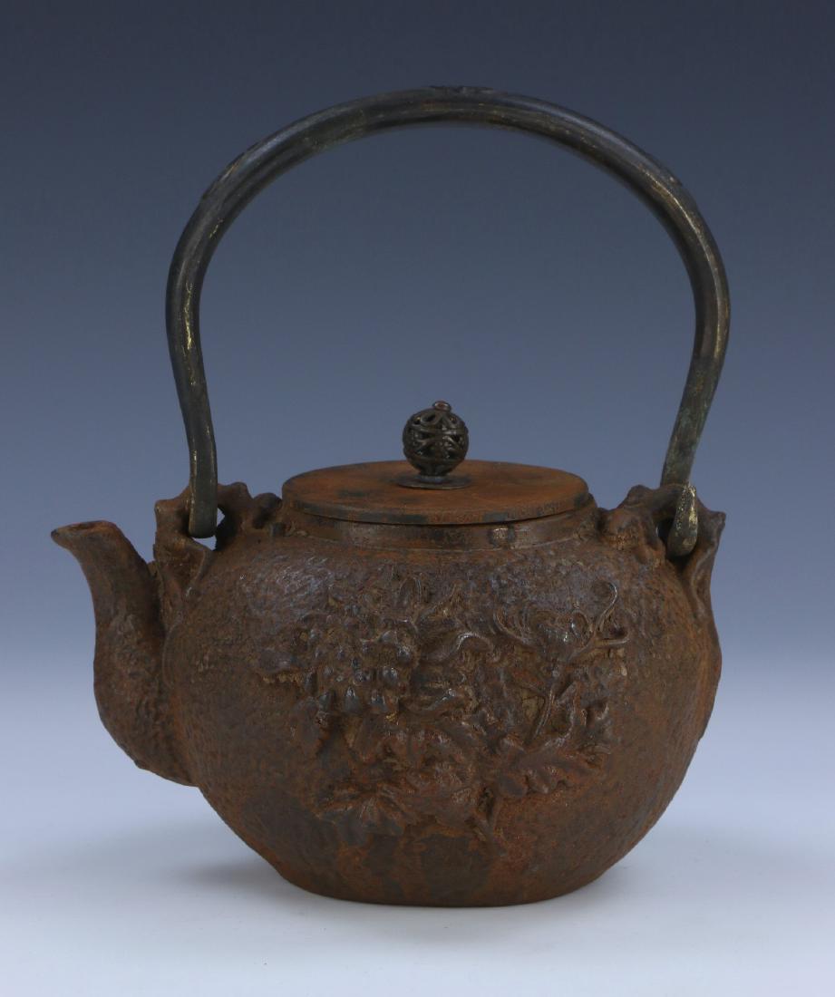 A JAPANESE ANTIQUE IRON TEAPOT: A Japanese Antique Iron Teapot: Of Compressed Globular Form, Exterior Body Finely Cast With Two Birds And A Sprouting Blossom Set in High Relief; Size: L: 7-1/2" (19.05cm)