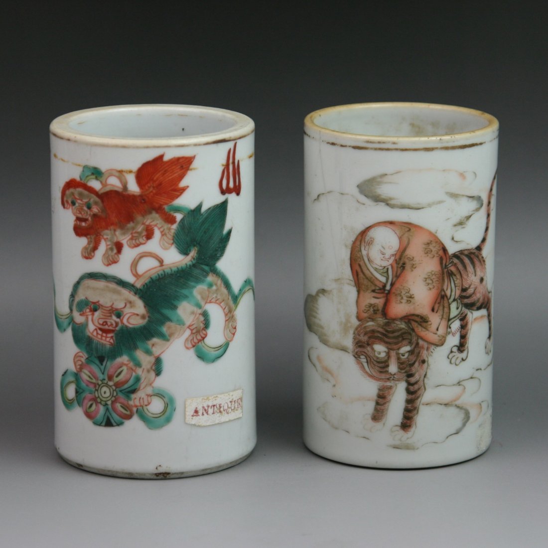 Two Chinese Famille Rose Porcelain Brush Pots: Two Chinese Famille Rose Porcelain Brush Pots: one depicting two lions chasing a ball: the other with the design of Tiger Taming Arhat sitting on the back of tiger among cloud scrolls: Both with six c