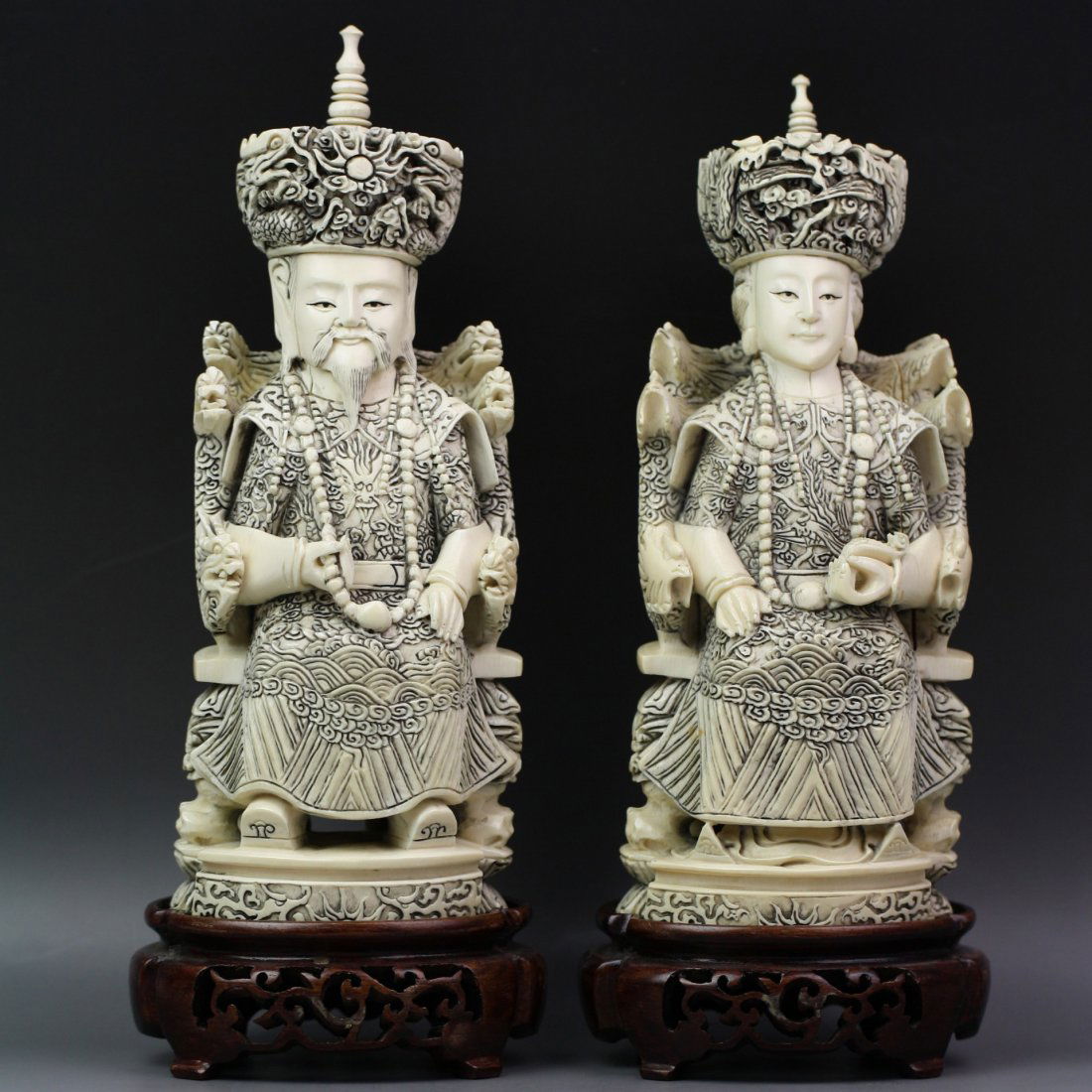 A Pair Of Chinese Carved Emperor And Empress: A Pair of Chinese Carved Emperor and Empress: elaborately carved, each with ornate robes and headdresses: he of dragon motif and clasping his beaded necklace in one hand: she of phoenix motif and hold