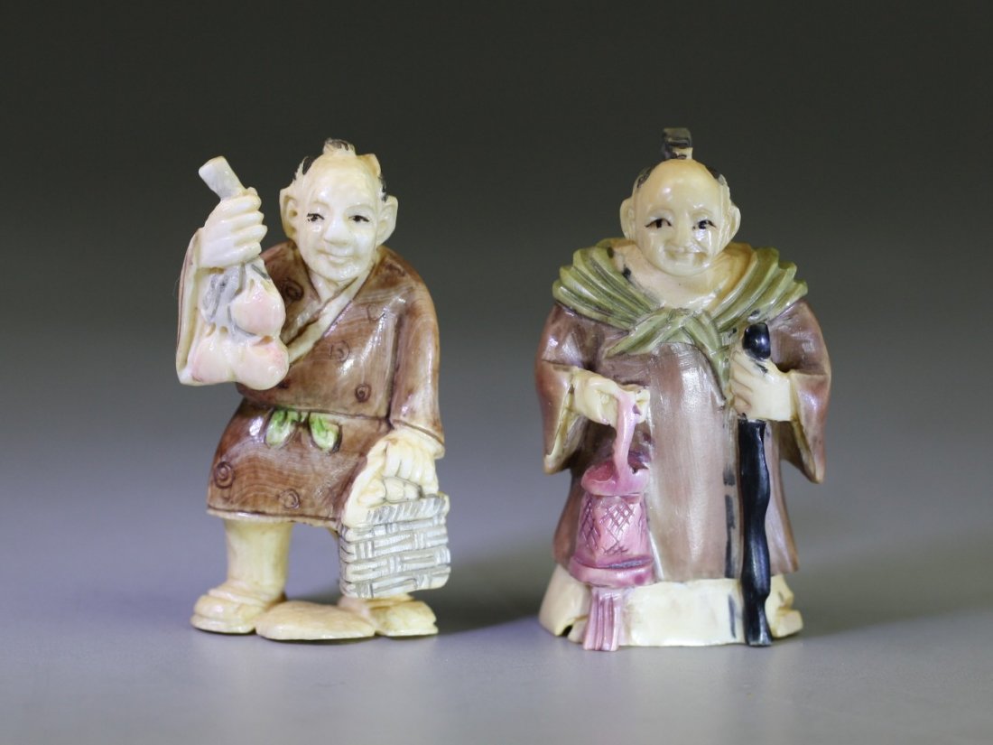 Pair Of Antique Polychrome Ivory Netsukes: Pair of Antique Polychrome Ivory Netsukes: one man and one lady standing while holding baskets and stick in their hands, both signed on the bases, 19th Century; Size: H: 2";