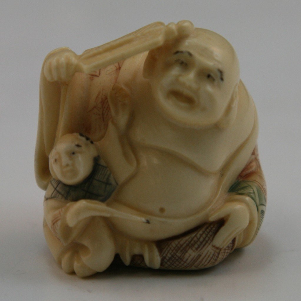 Antique Carved Ivory Netsuke: Figures: Antique carved ivory netsuke: Antique ivory netsuke: one heavy set man sitting down with an open robe on holding a fan to his head while a young child sits to his right side; Size: H: 1-1/4";