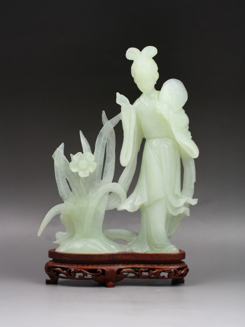 Chinese Jade Carving Of A Beauty: Chinese Jade Carving of A Beauty: well carved beauty dressing in long flowing robes tied with a sash at the waist, holding a fan at her shoulder with her left hand, while standing beside a large bloom