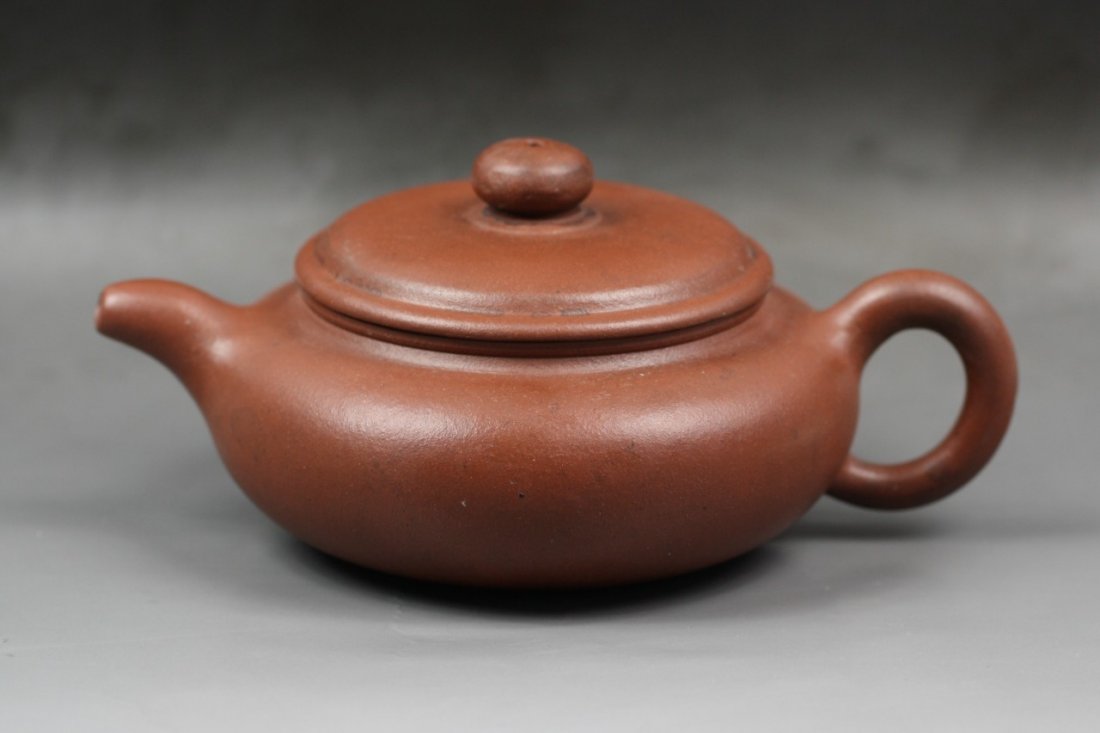 A Yixing Purple Clay Zisha Teapot By Gu, Jingzhou: A Yixing Purple Clay Zisha Teapot By Gu, Jingzhou: of compressed globular form, with a loop handle opposite the short cylindrical spout, the fitted rounded cover with knob, with the seal of the potter