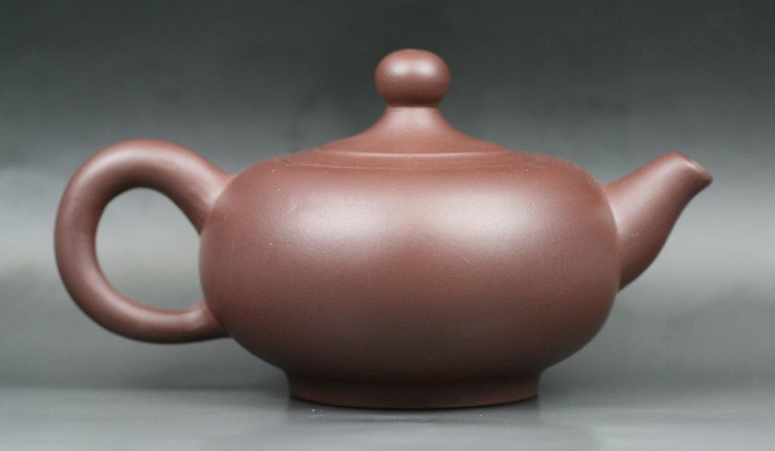 A Carved Yixing Purple Clay Zisha Teapot By Xu Hui: A Carved Yixing Purple Clay Zisha Teapot By Xu Hui: of compressed globular form with short cylindrical spout and C-shaped loop handle, with the seal of the potter Xuhui under the handle and another on