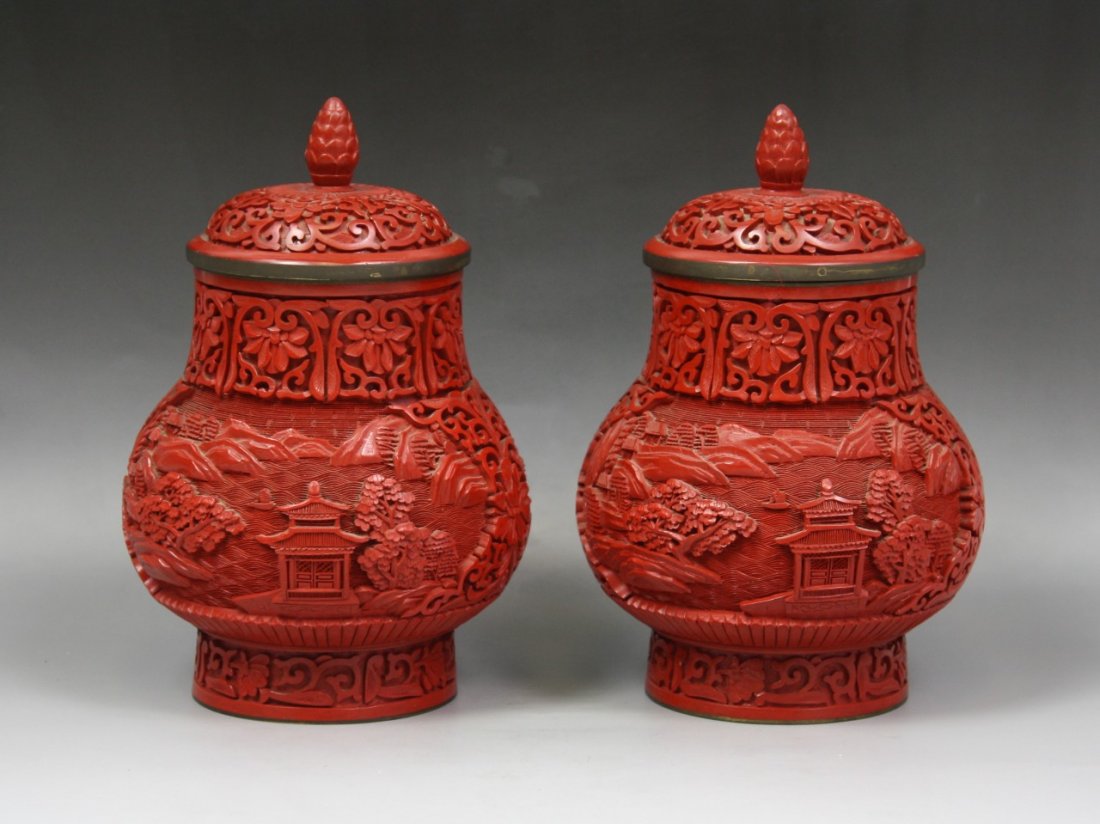 A Pair Of Chinese Carved Cinnabar Lacquer Vases: A Pair of Chinese Carved Cinnabar Lacquer Vases With Cover: each decorated with panels of mountainous riverscape with borders of flowers amid vines, with domed covers and knobbed finials, early 20th C