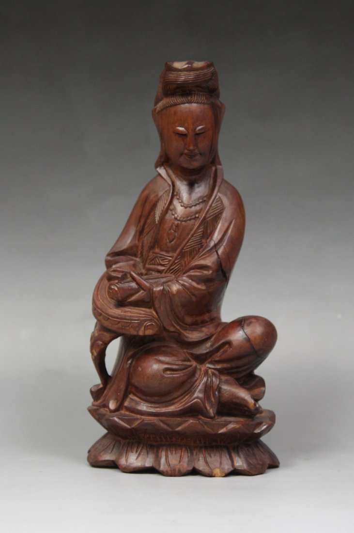 A Chinese Antique Wood Figure Of Guanyin: A Chinese Antique Wood Figure of Guanyin: finely carved from the wood with warm brown tone as a Guanyin seated on a double lotus plinth with a royal ease wearing robes, holding a book-like object in h