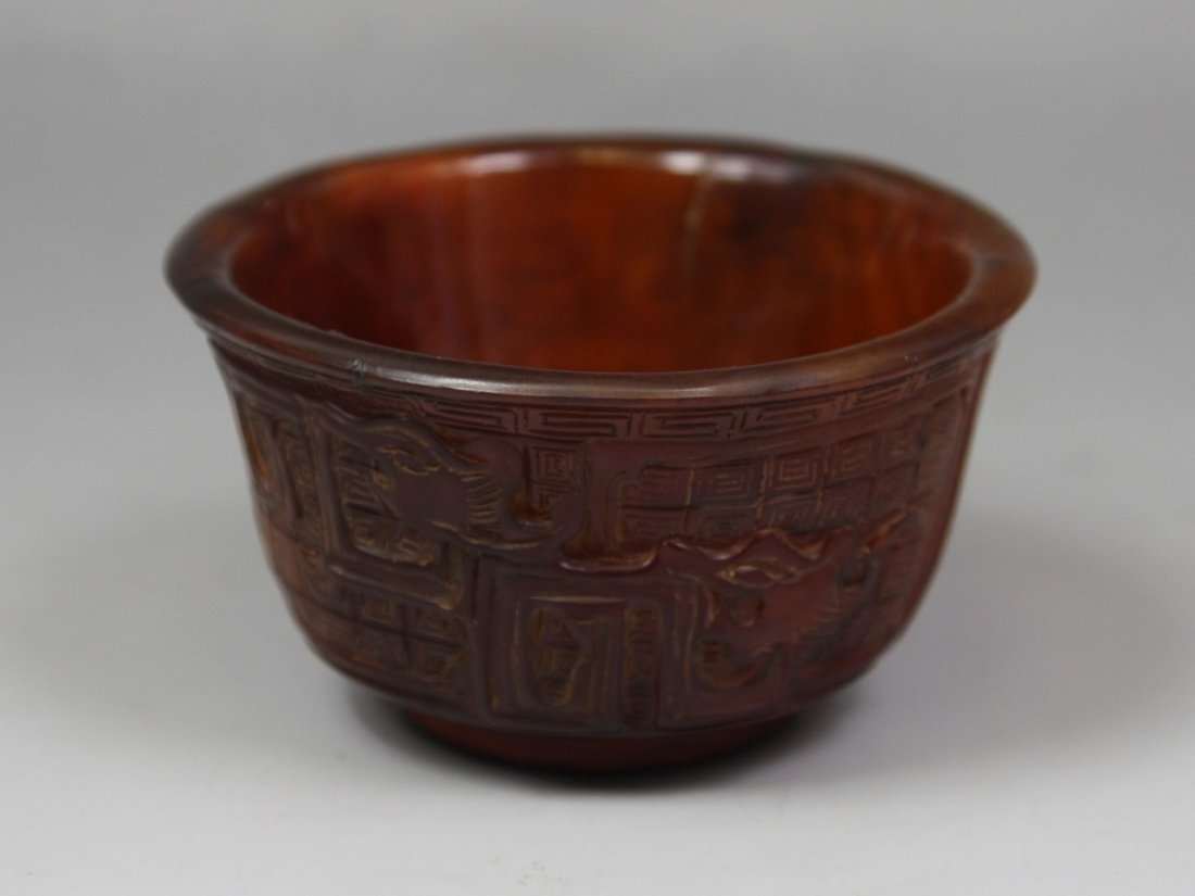 A Chinese Carved Horn Cup: A Chinese Carved Horn Cup: carved from the horn with dark warm brown tone as a cup with slightly flaring rim, continuously carved with classic scrollwork; Size: D: 3-3/4"