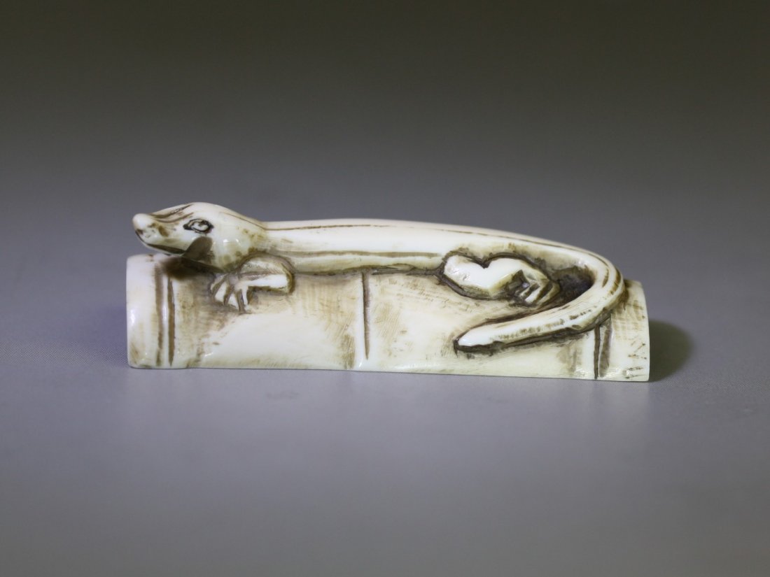 An Antique Ivory Netsuke: Lizard: An Antique Ivory Netsuke: a lizard resting on a bamboo tube, signed on the base, 19th Century; Size: L: 2"